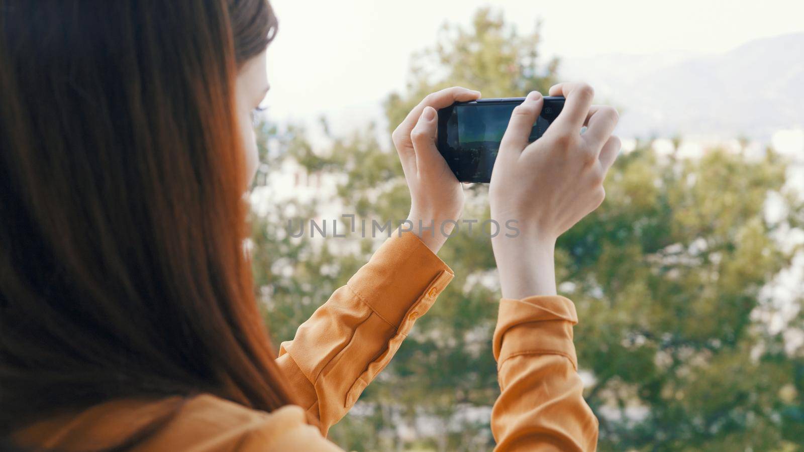 woman with phone in hand takes pictures of nature on camera vacation landscape. High quality photo
