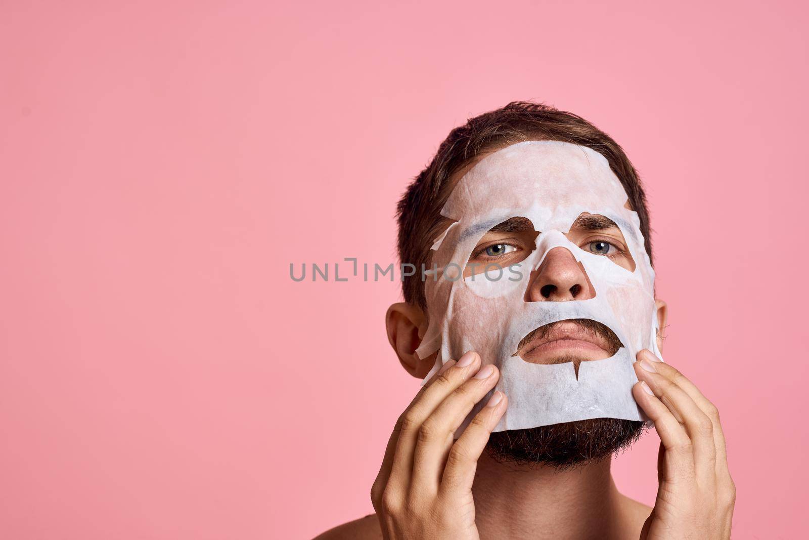 Man with bare shoulders clean skin face care pink background. High quality photo