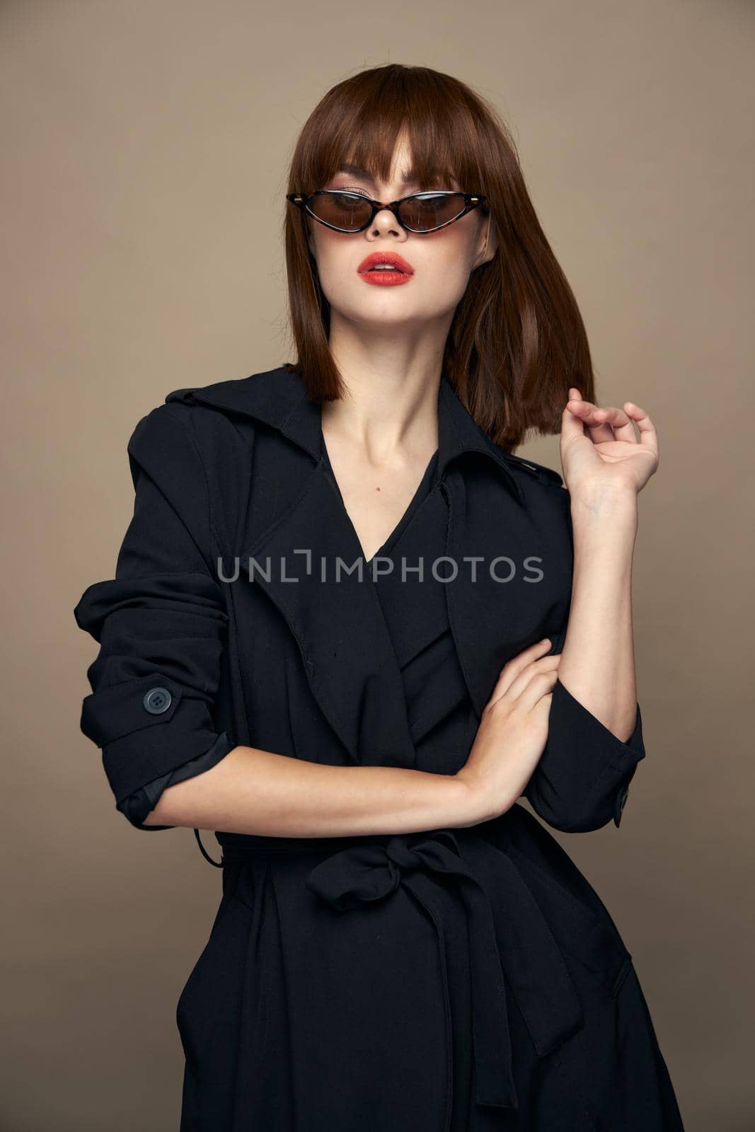 Stylish Woman Red lips sunglasses black coat beige isolated background