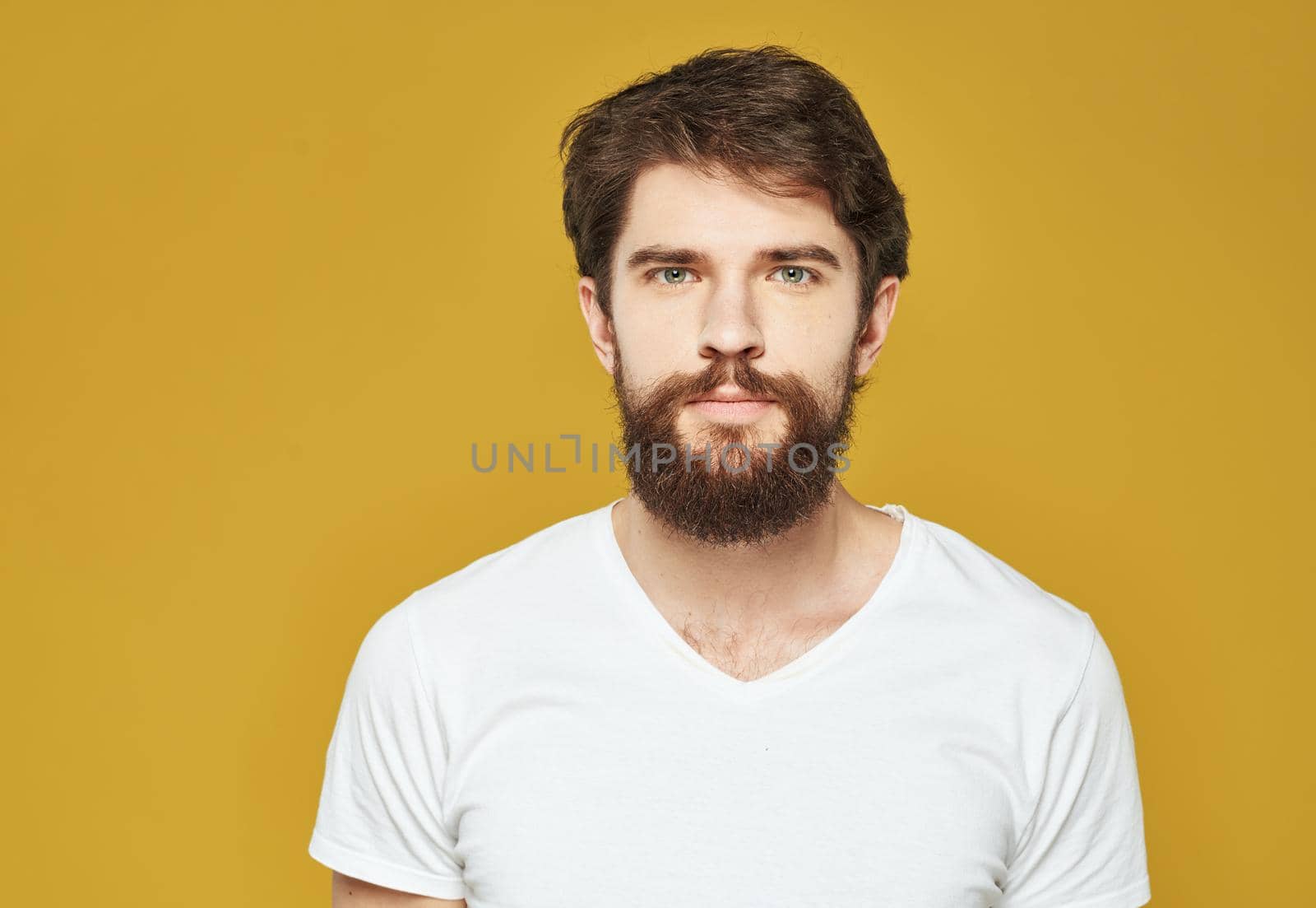 Brunette man on a yellow background in a white t-shirt cropped view. High quality photo