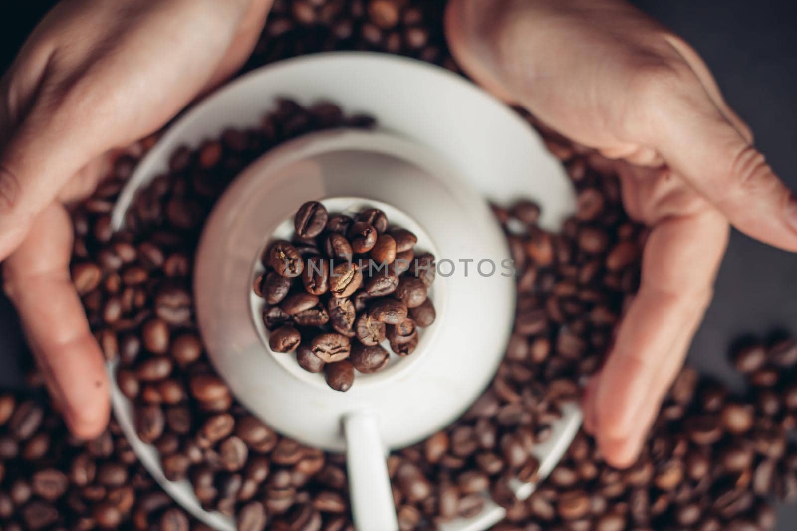 coffee beans on a saucer and an inverted white cup on a dark background female hands. High quality photo