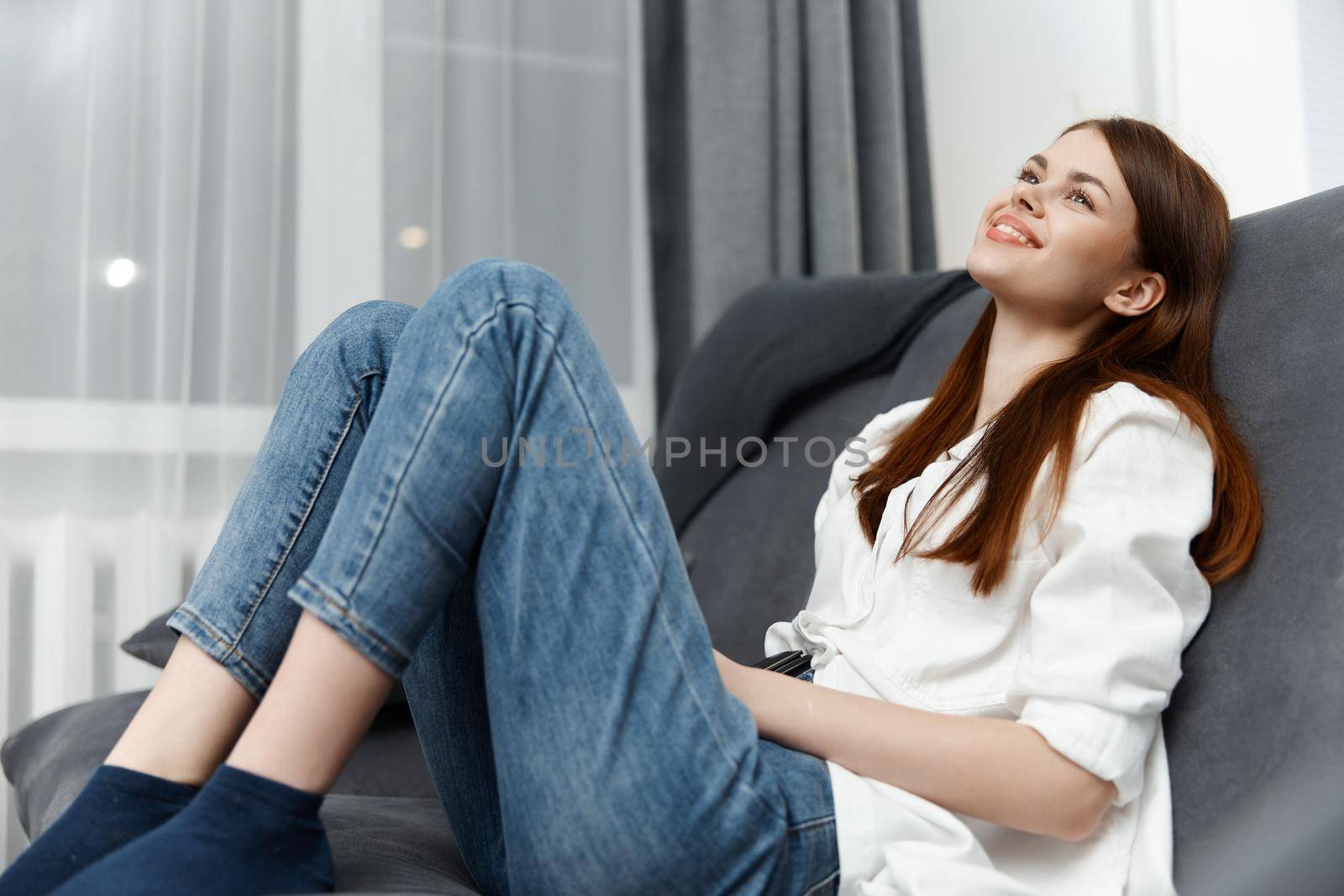 cheerful woman at home sitting on the couch relaxing interior by SHOTPRIME