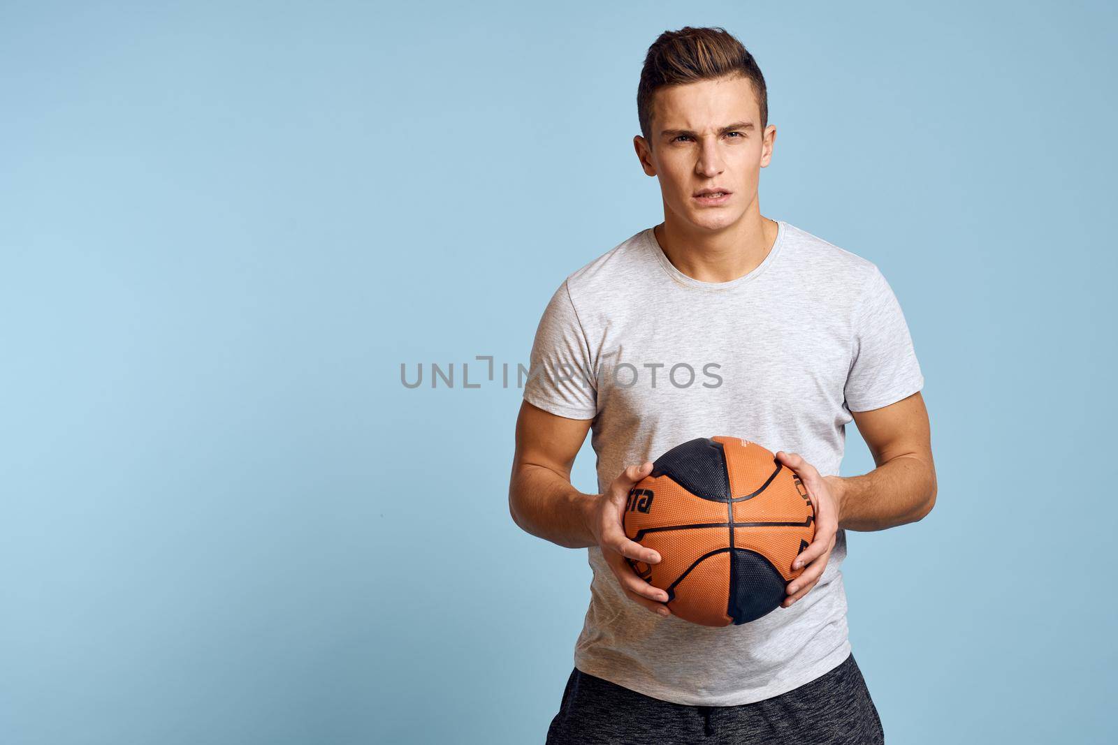 Sporty man playing ball workout lifestyle studio blue background by SHOTPRIME