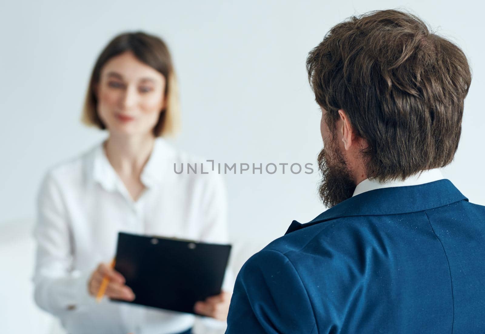 A man in a blue jacket and a woman in a shirt documents light background indoor. High quality photo