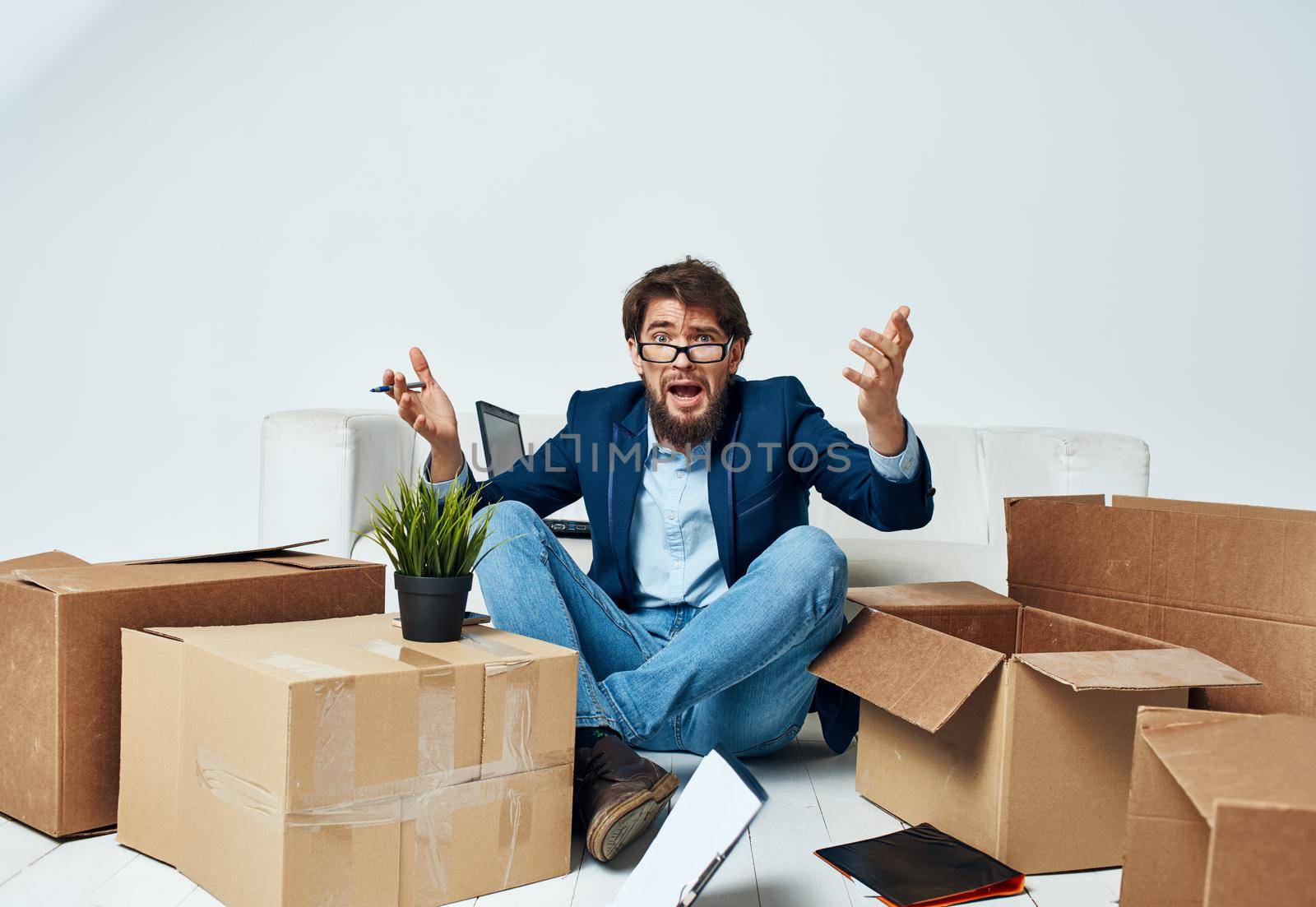 Emotional Man sits on the floor next to boxes unpacking a move Professional by SHOTPRIME