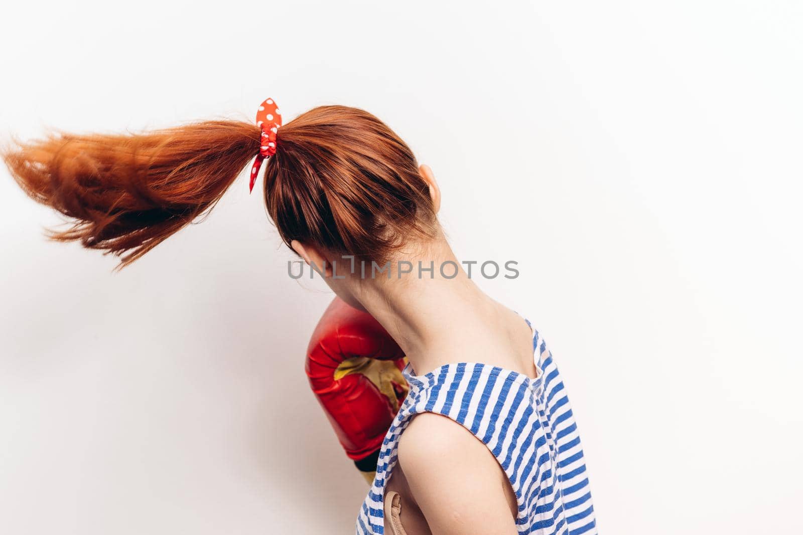 woman practicing a blow in boxing gloves on a light background striped t-shirt model. High quality photo