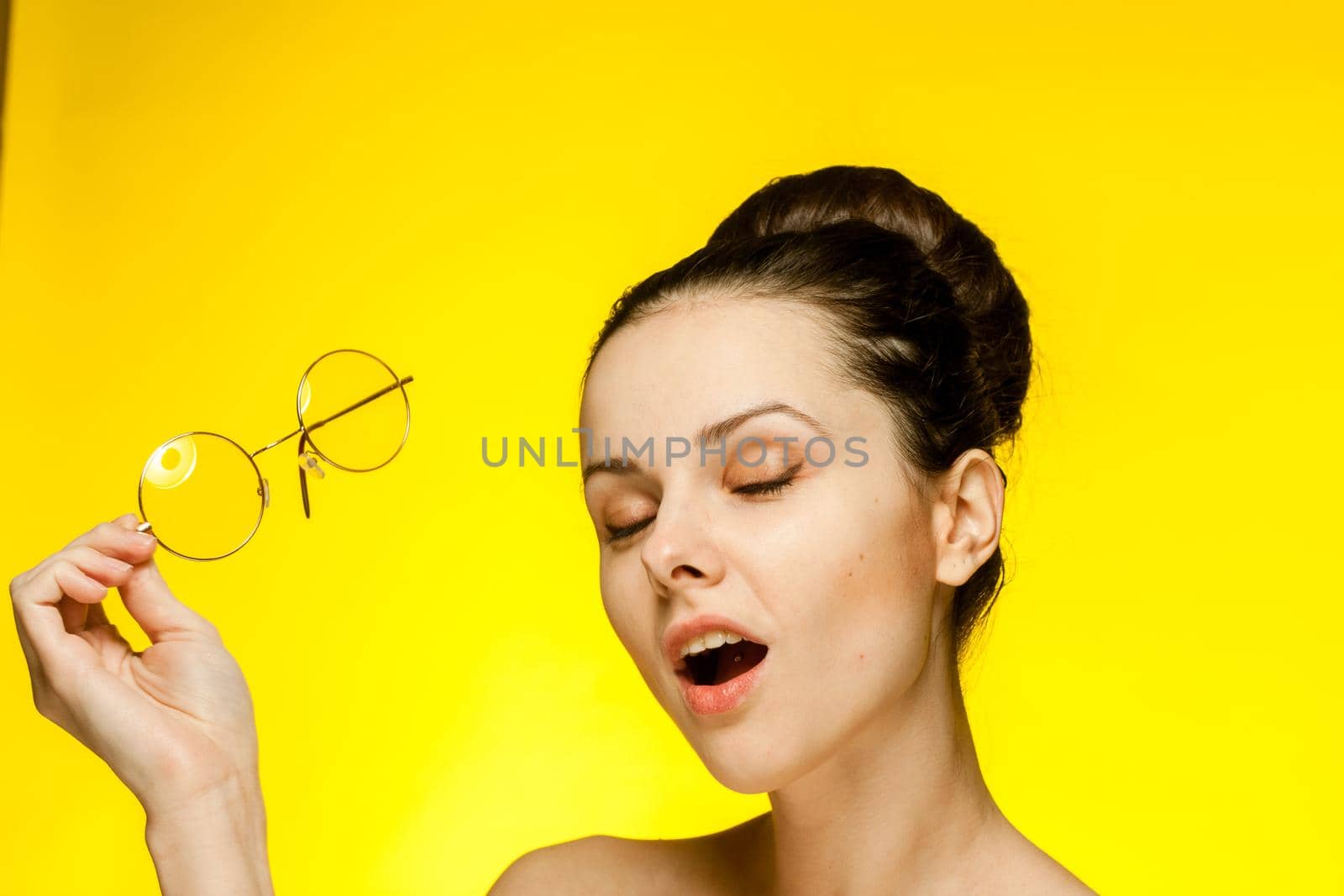 brunette with bare shoulders yellow glasses attractive look. High quality photo