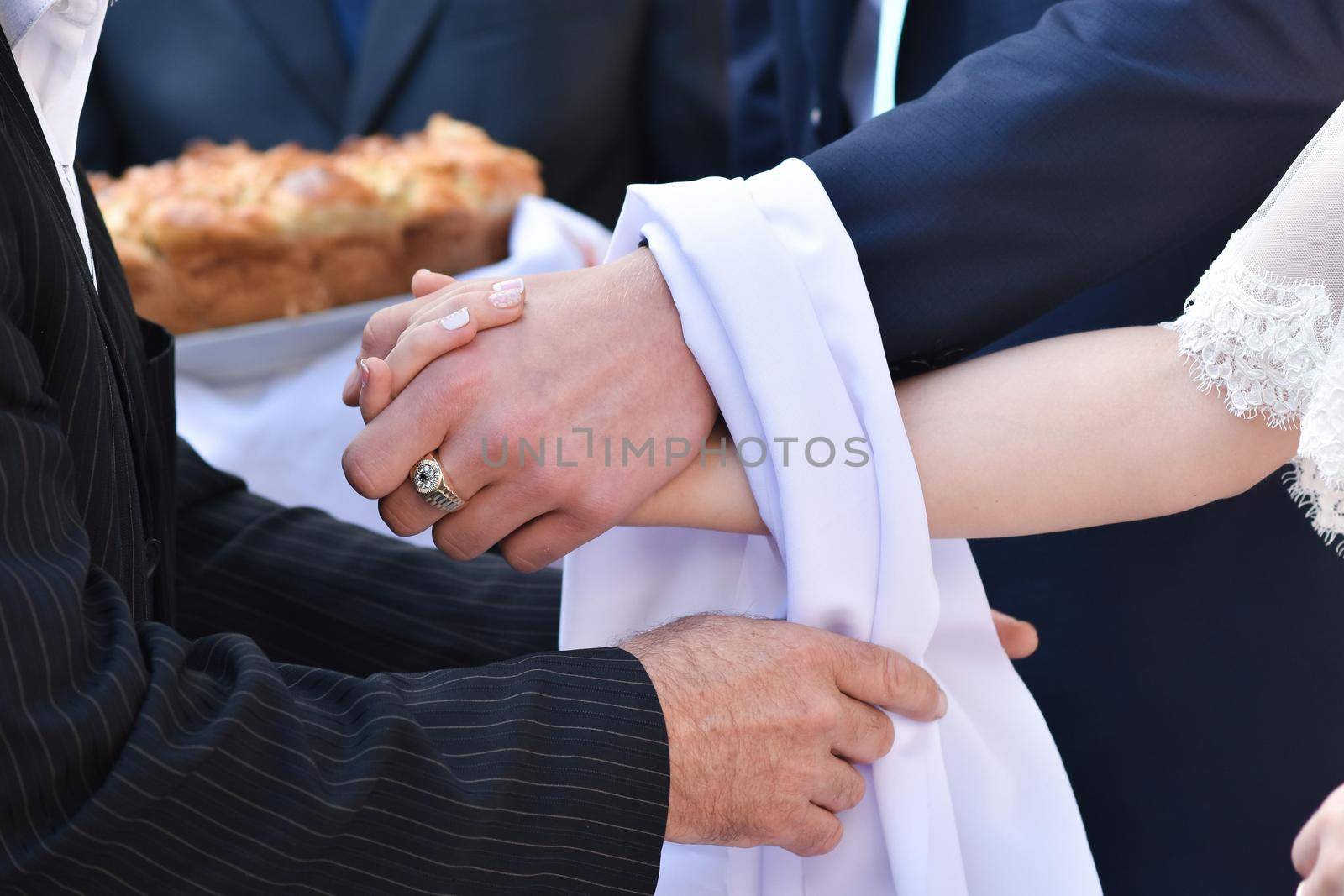 Wedding customs. The bride and groom hold hands. The parent ties their hands together with a white towel. A symbol of a long life together. Traditional wedding in Russia and Ukraine.