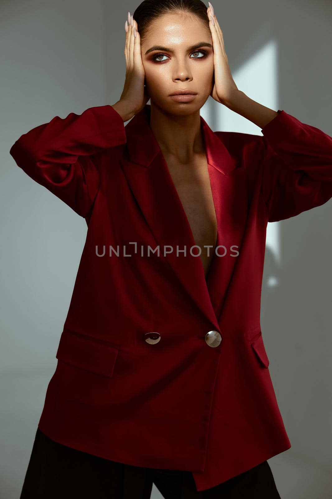 attractive woman in red jacket holding bright makeup face. High quality photo
