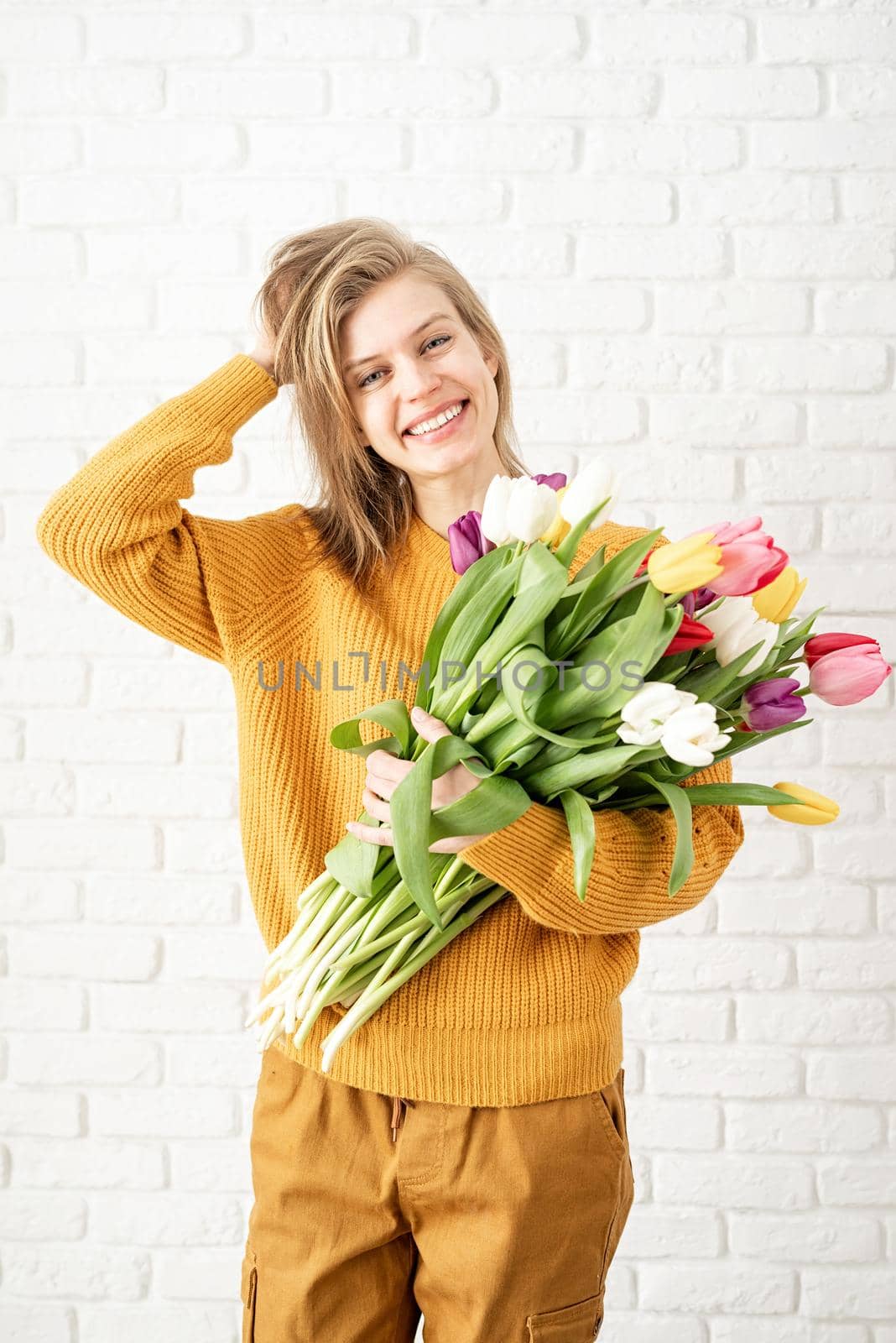 Mothers Day, Women's Day concept. Spring holidays. Happy young woman holding bouquet of tulips