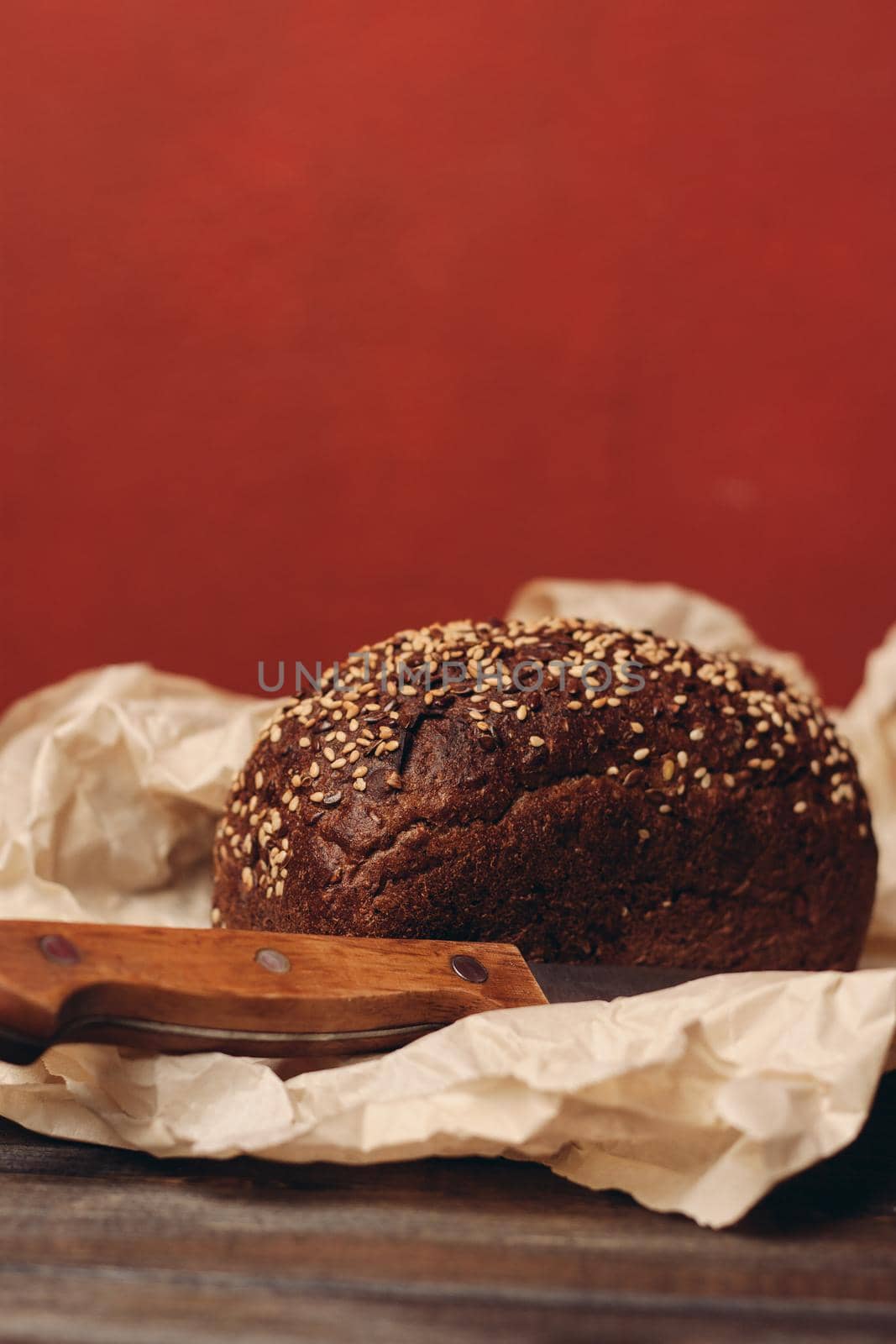 rye bread on paper packaging on a red background and a wooden table with a sharp knife. High quality photo