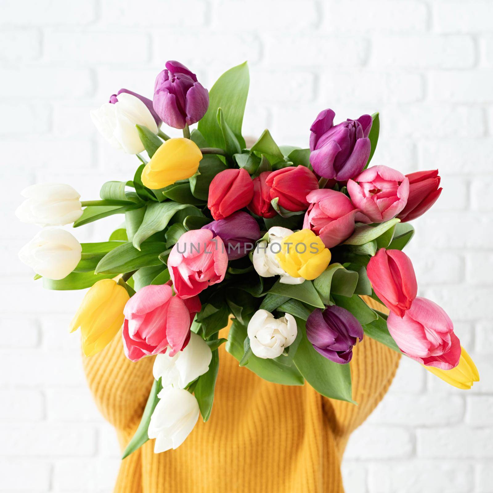 woman holding bouquet of tulips in front of her face by Desperada