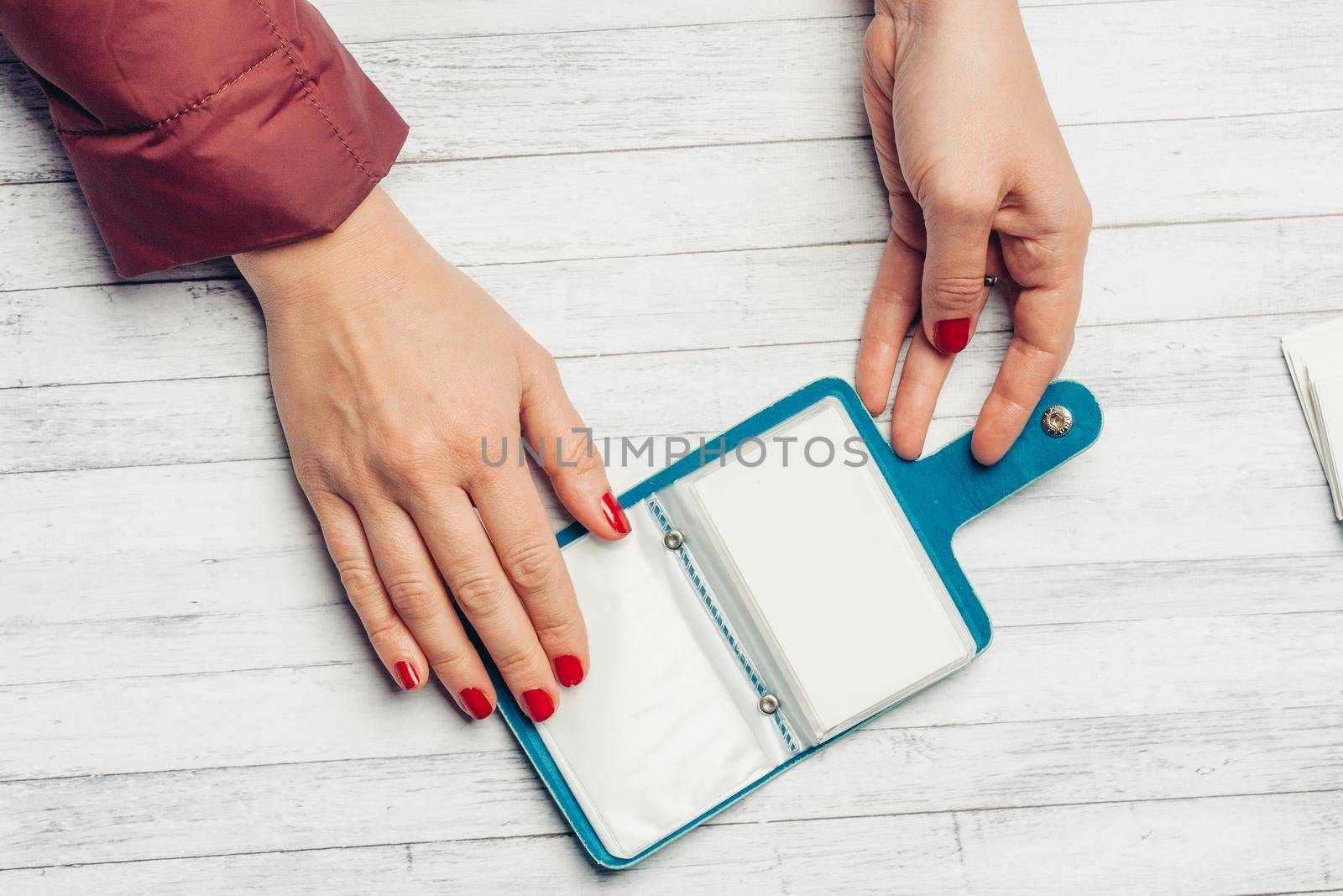 blue business card holder in female hands on a wooden table top view. High quality photo