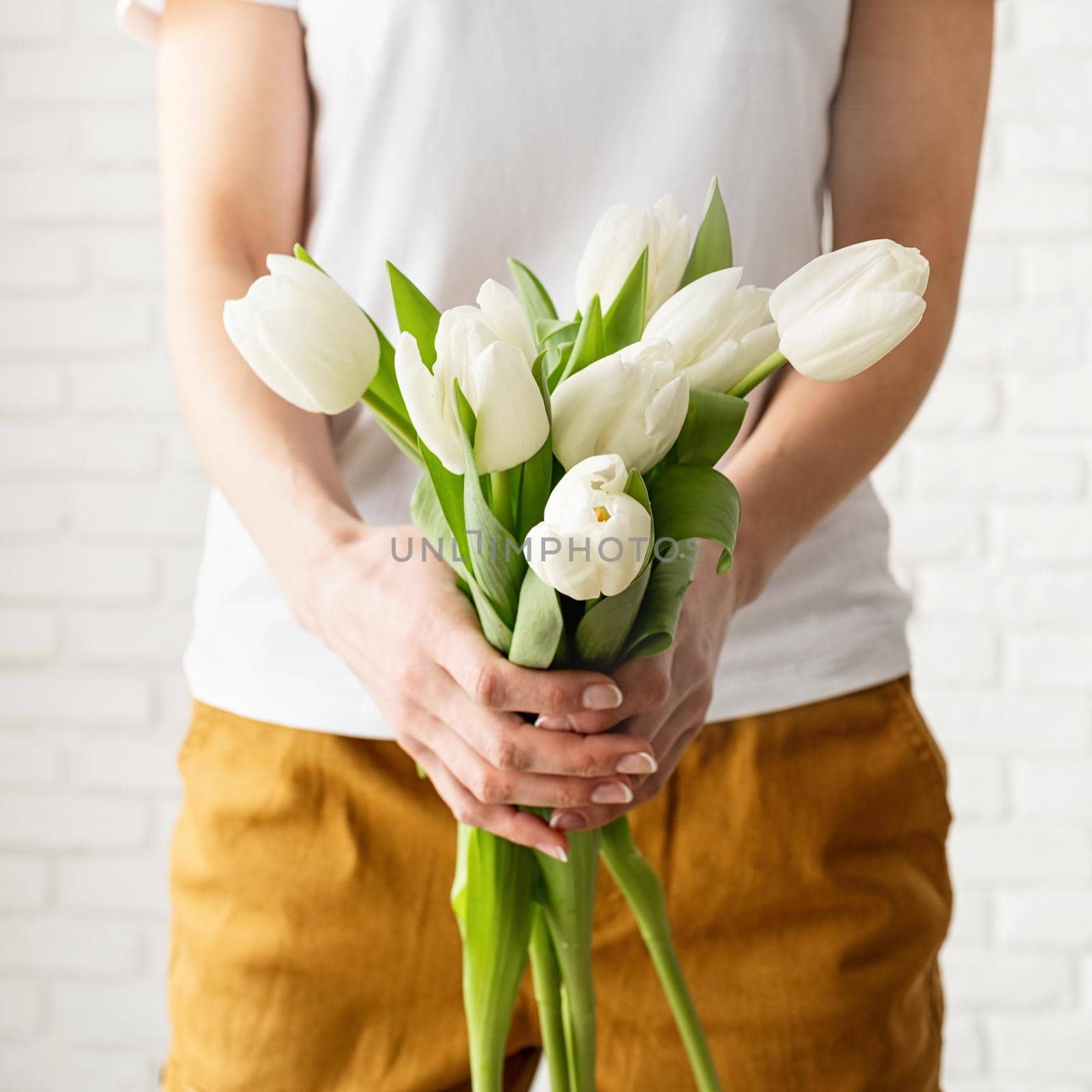 woman in yellow clothes holding bouquet of white tulips by Desperada