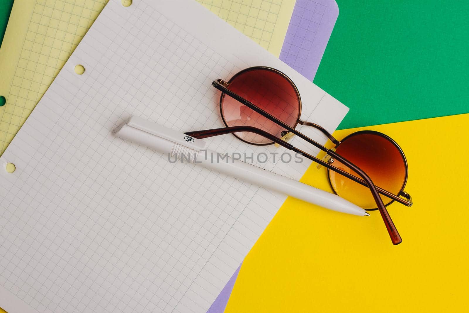 multicolored sheets of paper on colored background and pen office notepad clip glasses. High quality photo