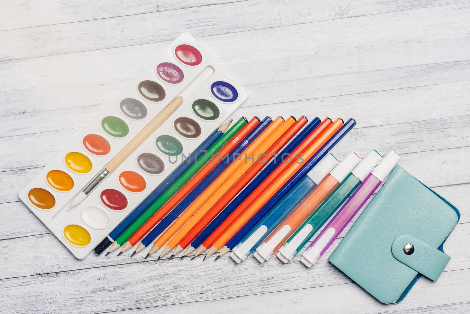 stationery on wooden table card holder pencils and watercolor paints by SHOTPRIME
