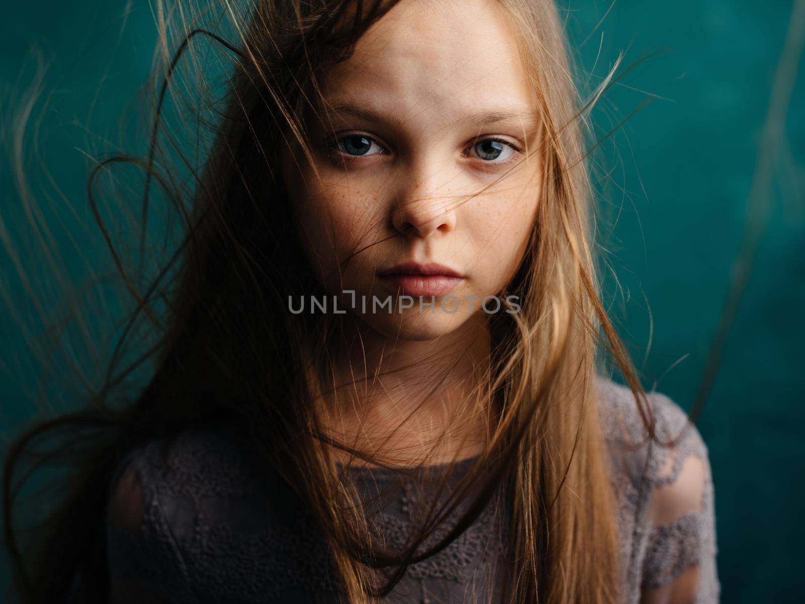 A girl with shaggy hair on a turquoise background and a gray sundress. High quality photo
