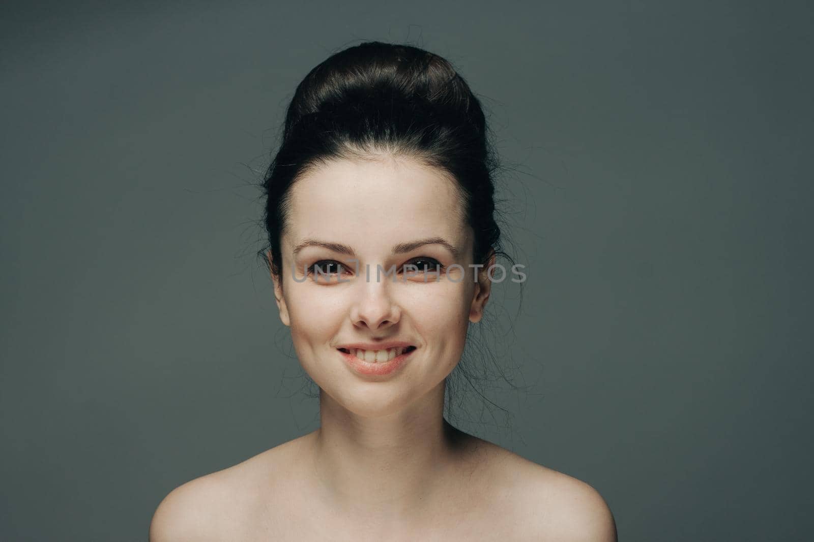 beautiful woman smiling on gray background naked shoulders cropped view hairstyle. High quality photo
