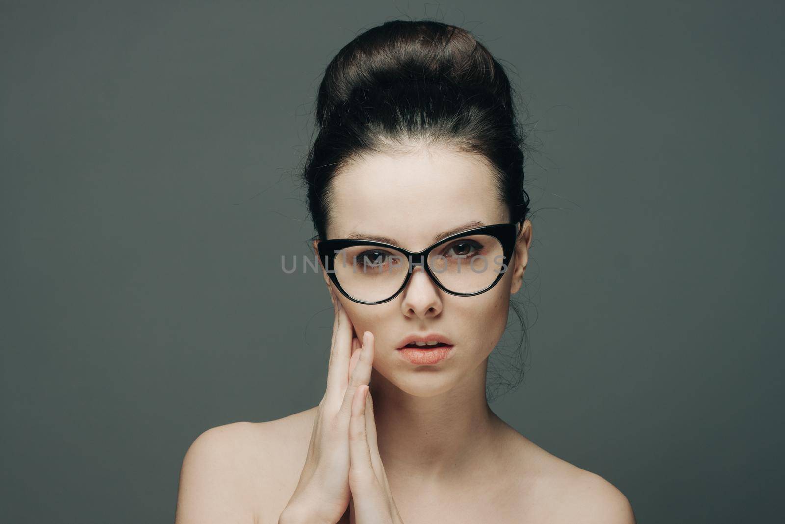 portrait of beautiful brunette with glasses naked shoulders gesturing with hands. High quality photo