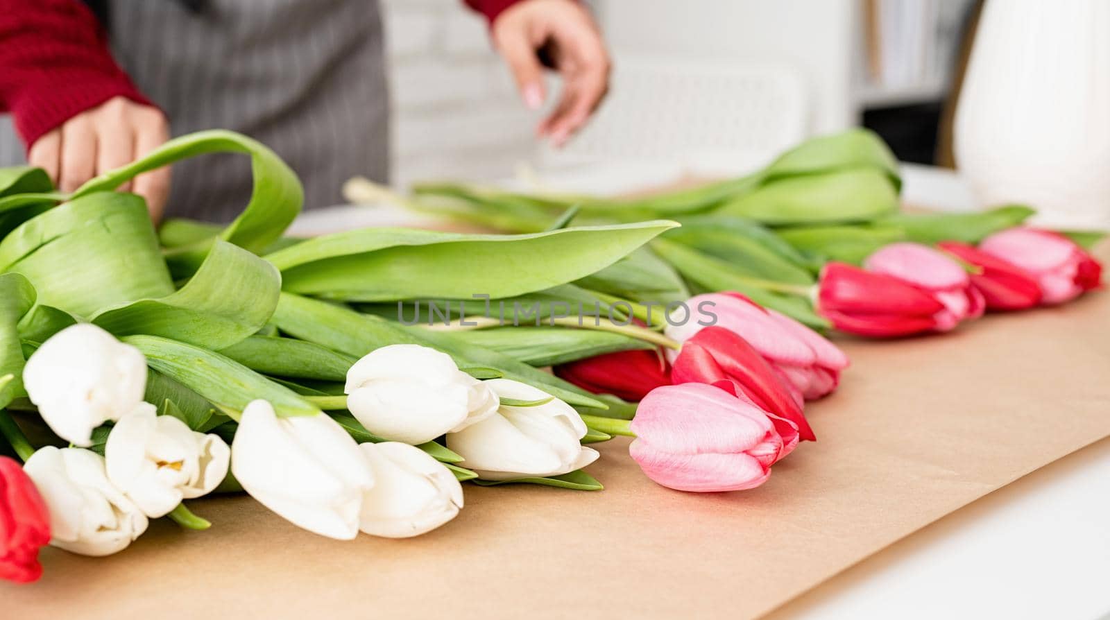 Woman florist making a bouquet of fresh colorful tulips by Desperada