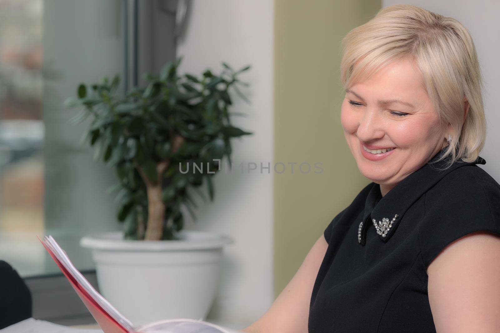 A female director working in an office is sitting at a table, analyzing business statistics, checking documents. Close-up.