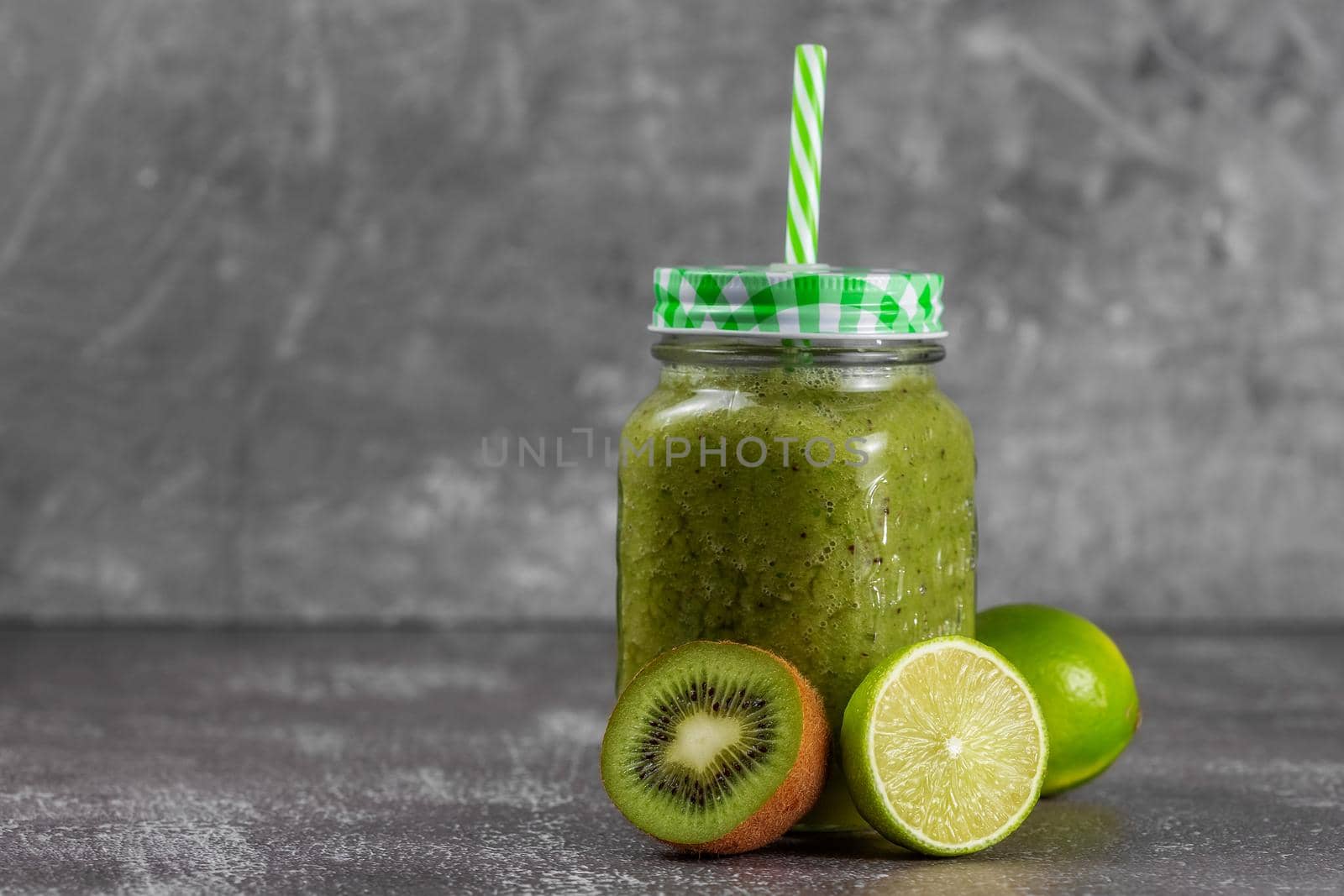 Step 5. Jar a mug with ready-made banana, kiwi and spinach smoothie with apple juice. Fresh citrus fruits and kiwis lie next to the jar