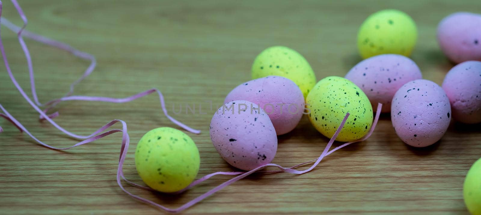Closeup shot of Colorful yellow and pink easter egg placed on top of a wooden table