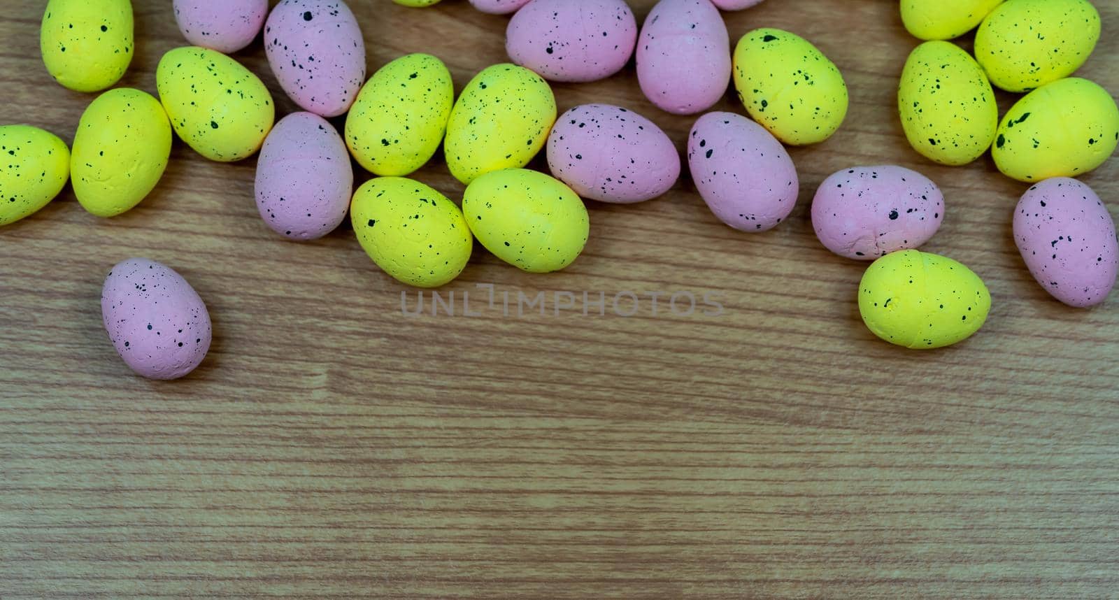 Closeup shot of Colorful yellow and pink easter egg placed on top of a wooden table