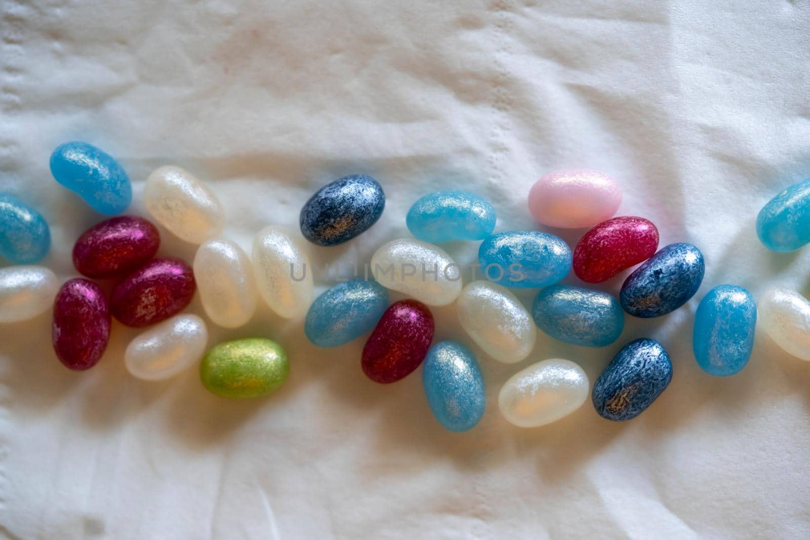 Colorful candy beans placed on top of a white background crumpled paper