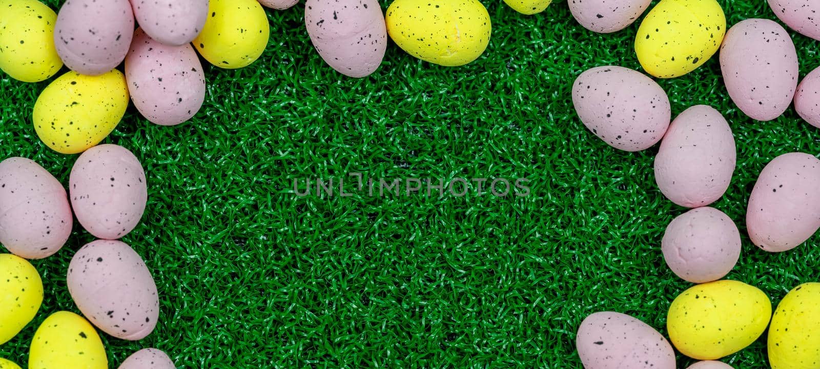 Colorful Yellow and Pink easter egg with freckle patterns on grass with copy space