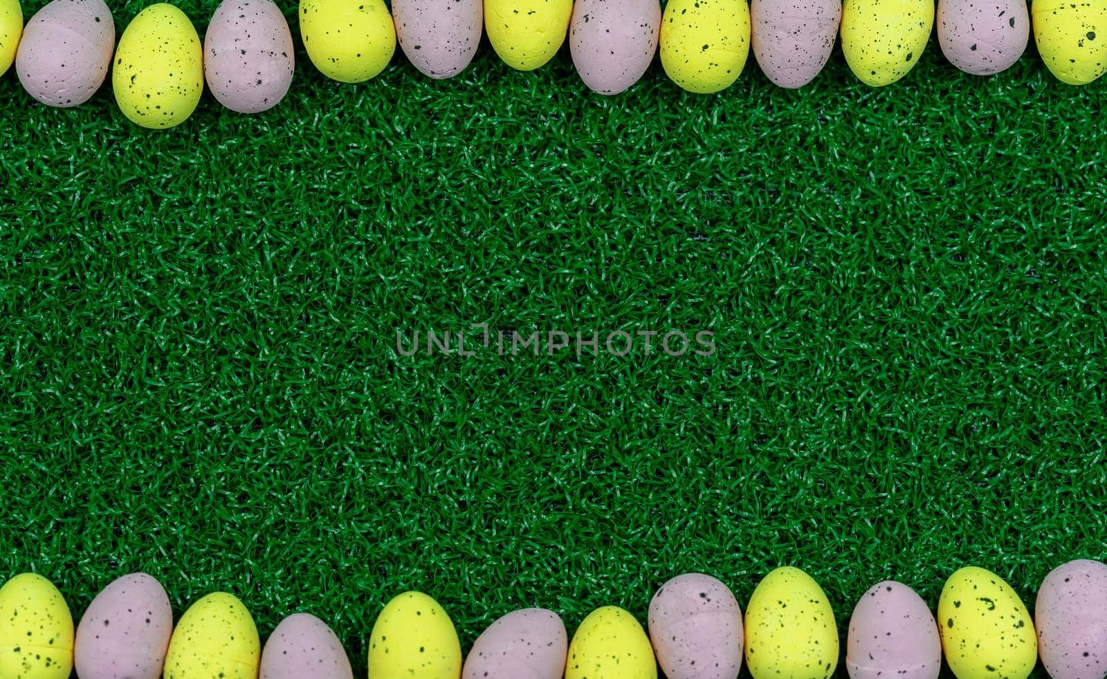 Colorful Yellow and Pink easter egg with freckle patterns on grass with copy space