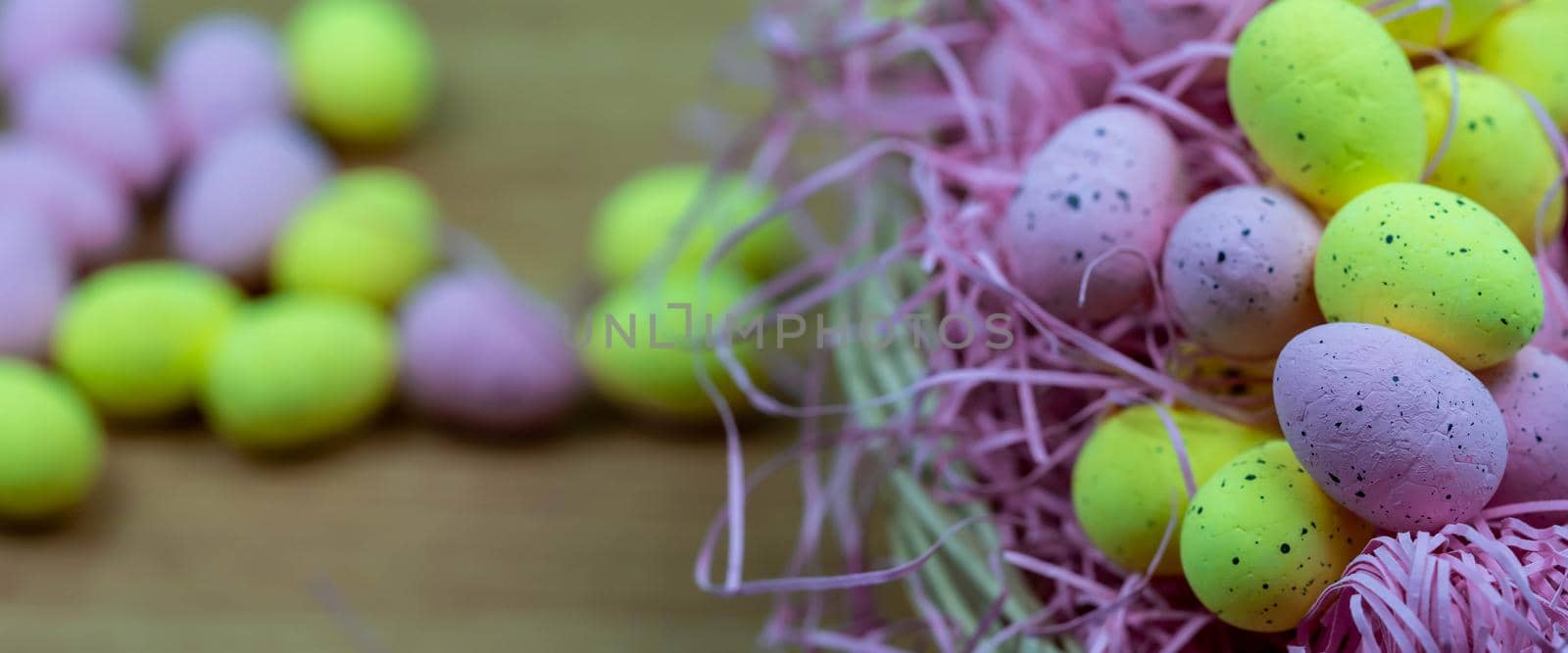 Colorful Yellow and Pink easter egg with freckle patterns on wooden table with copy space. Pink and Yellow easter egg inside a basket