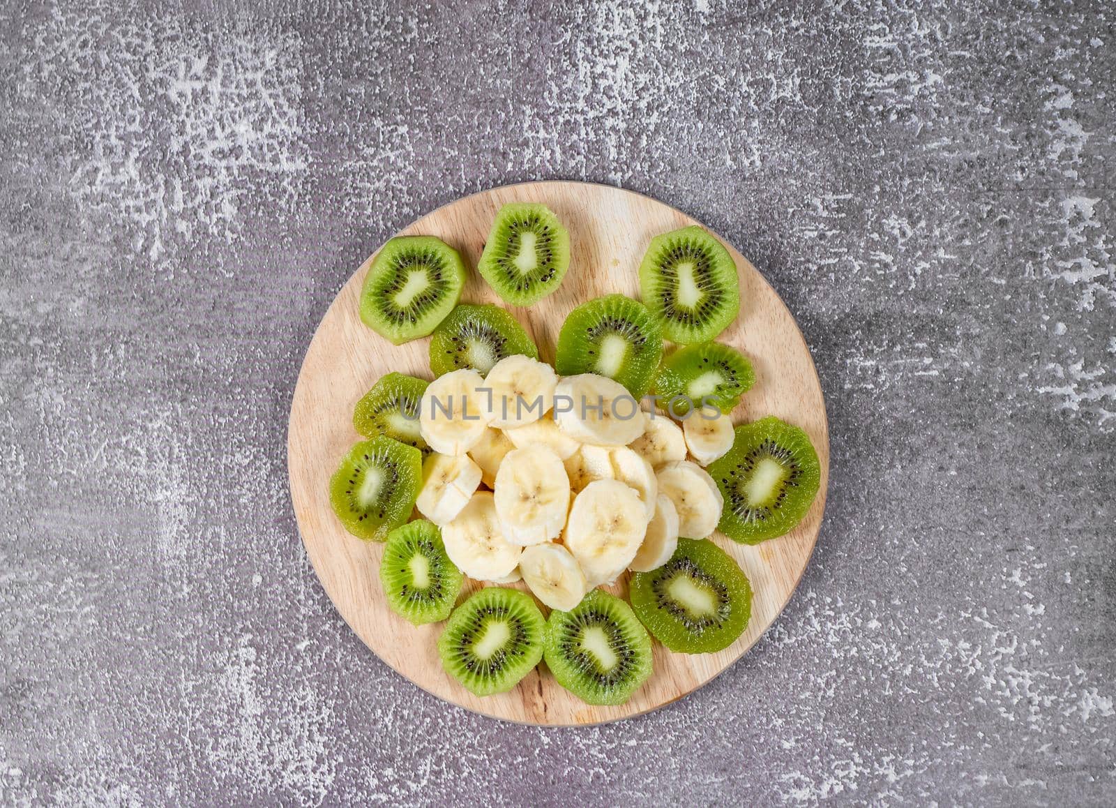 Step 4. Slicing fruit for smoothies. Peeled banana and kiwi are cut on a cutting board.