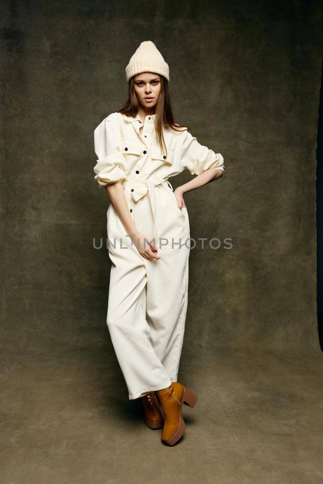 attractive brunette in a suit and boots in full growth on a brown background. High quality photo