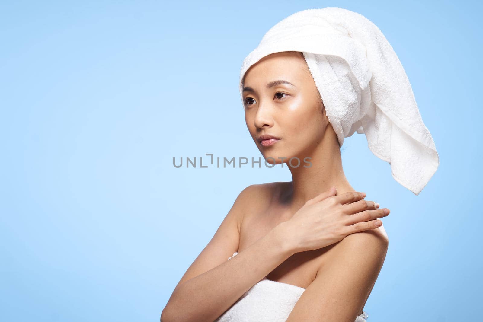 woman asian appearance naked shoulders towel on head blue background studio skin care. High quality photo