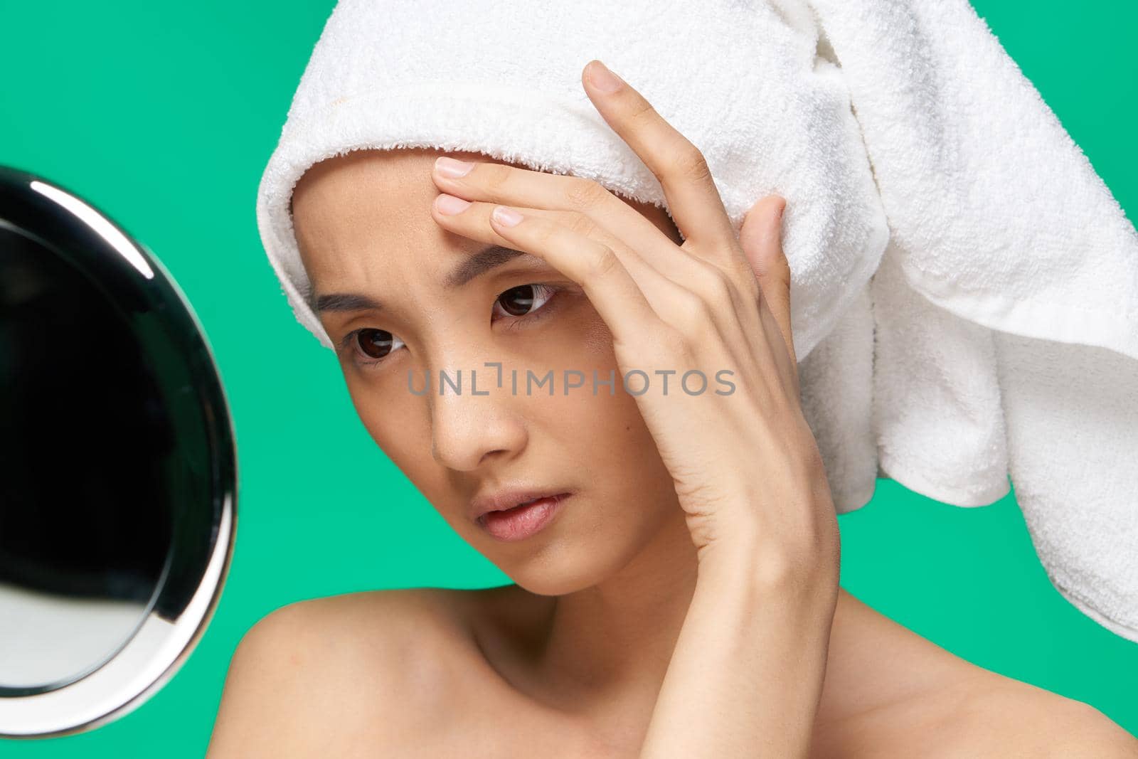 pretty asian woman looking in the mirror and touching her face close-up. High quality photo