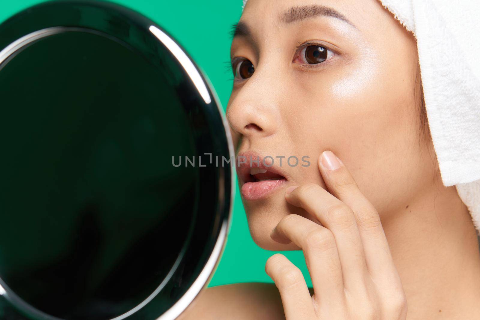 woman of asian appearance towel on head clean skin touching face mirror with hands. High quality photo
