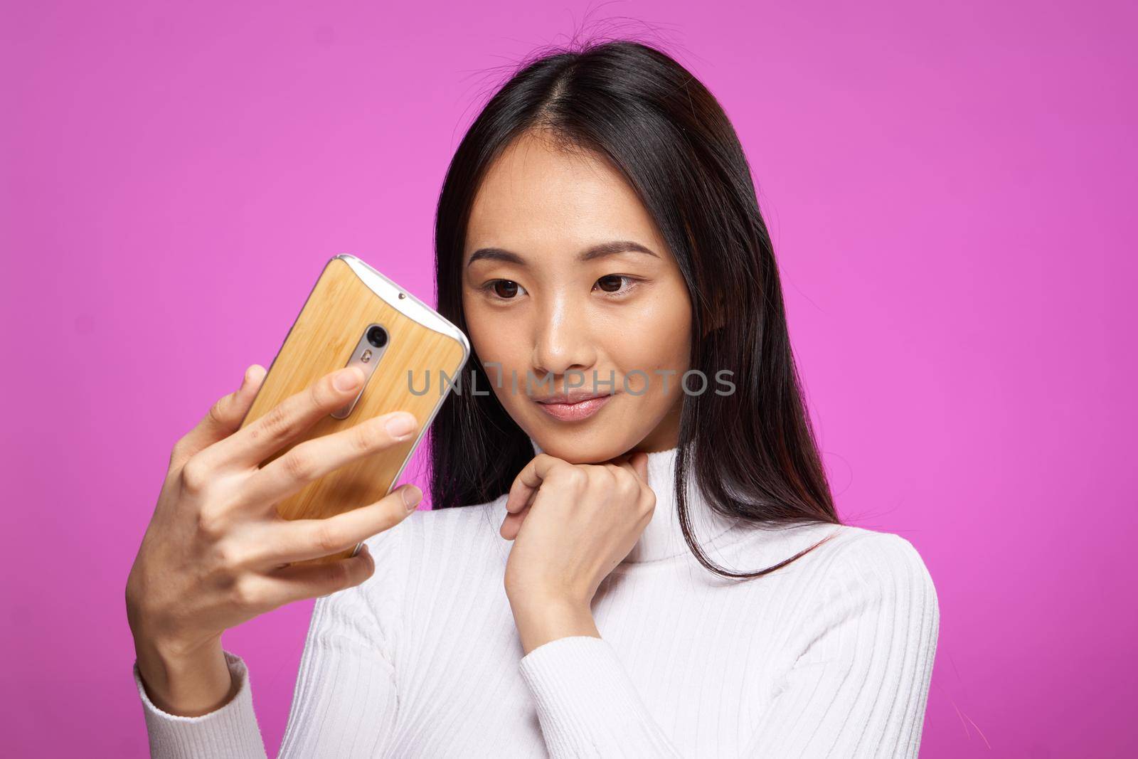 cute brunette phone in hand internet technology lifestyle pink background. High quality photo