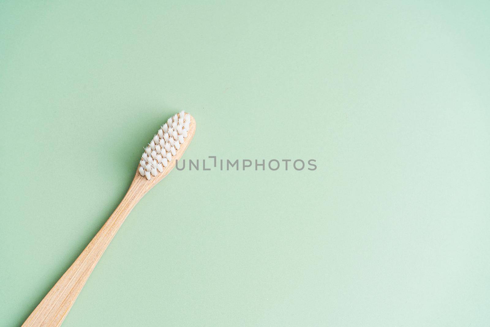 Eco friendly dental health antibacterial bamboo wood toothbrush on green background by Try_my_best