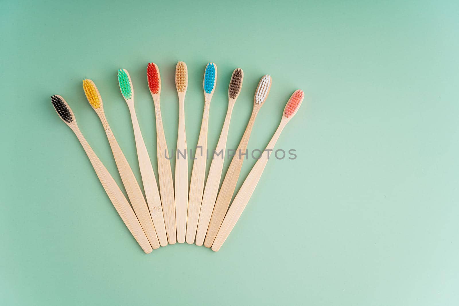 A set of Eco-friendly antibacterial toothbrushes made of bamboo wood on a light green background. Environmental care trends by Try_my_best