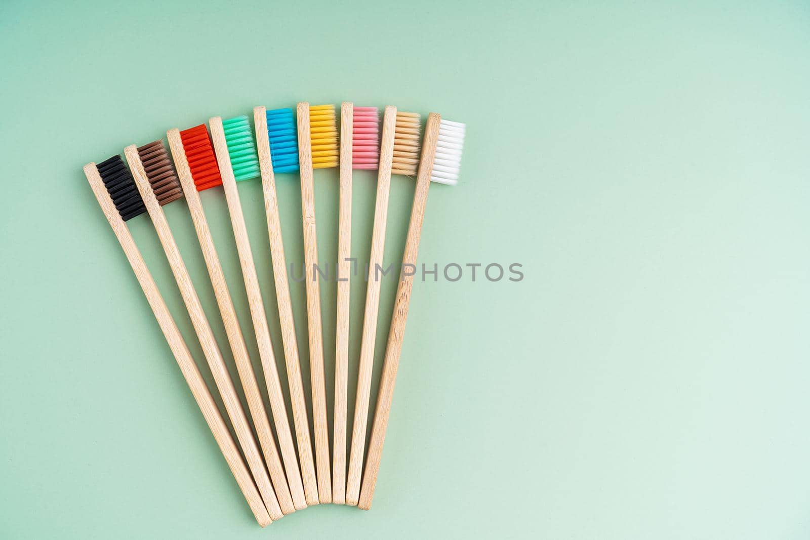 A set of Eco-friendly antibacterial toothbrushes made of bamboo wood on a light green background. Environmental care trends.