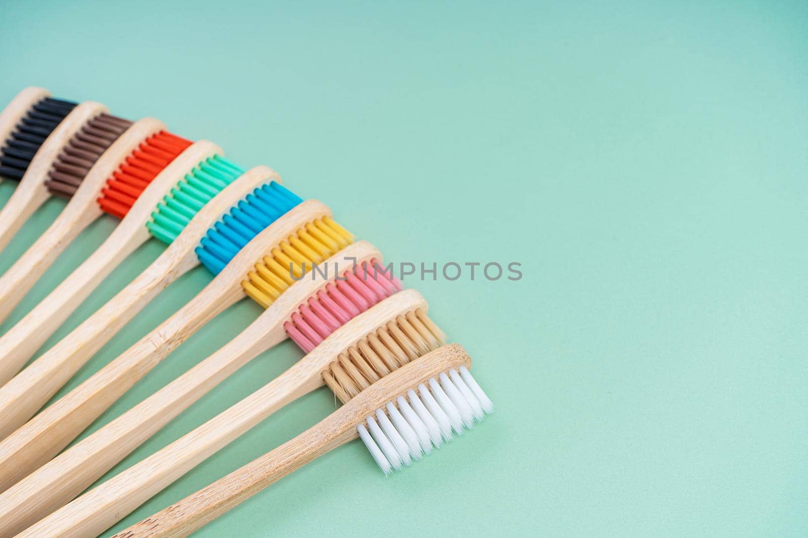 A set of Eco-friendly antibacterial toothbrushes made of bamboo wood on a light green background. Environmental care trends.