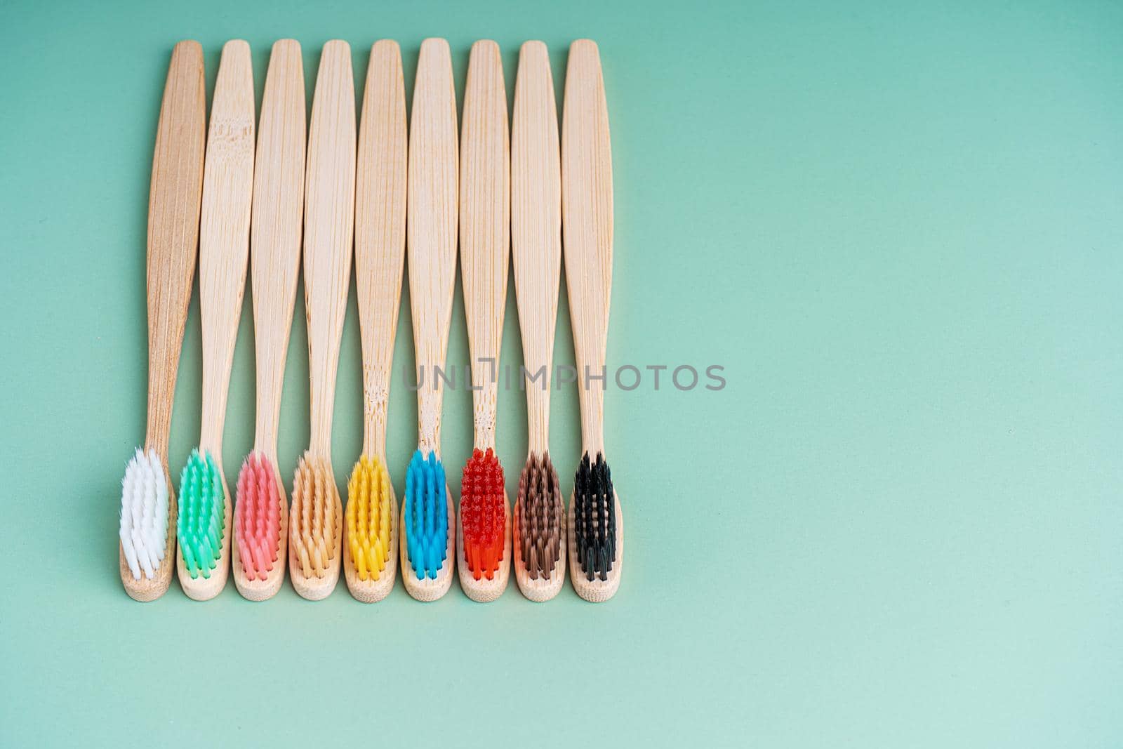 A set of Eco-friendly antibacterial toothbrushes made of bamboo wood on a light green background. Environmental care trends.