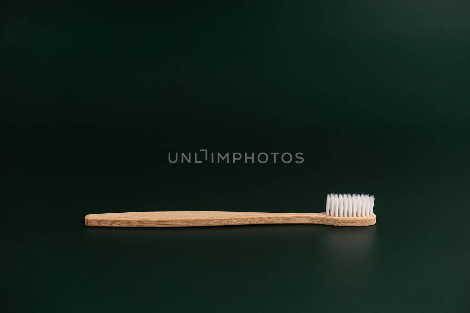 Eco friendly dental health antibacterial bamboo wood toothbrush on dark green background by Try_my_best