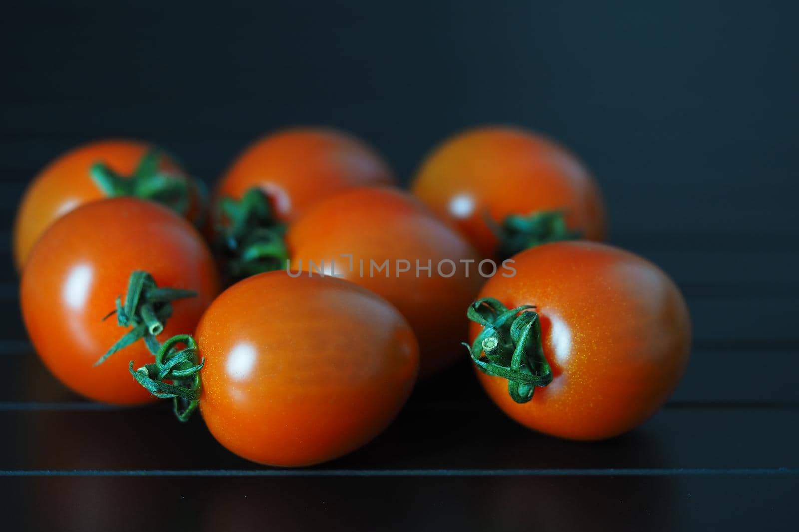 Red ripe cherry tomatoes on a black background close-up. High quality photo