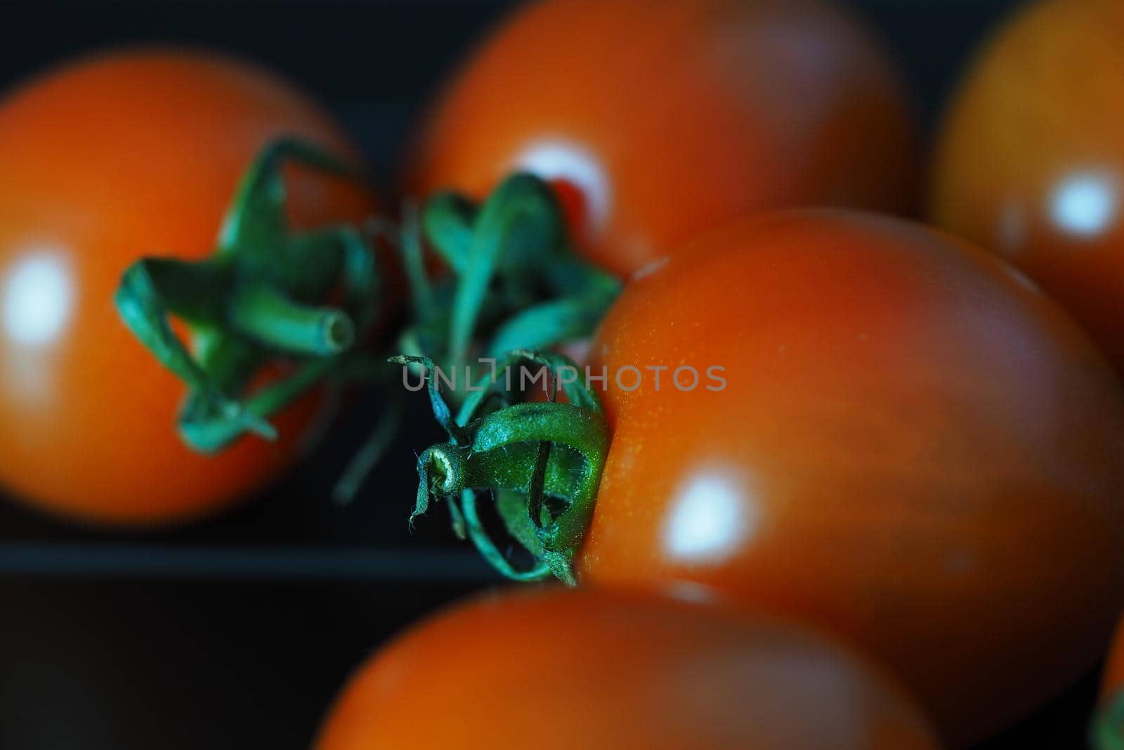 Red ripe cherry tomatoes on a black background. by Olga26