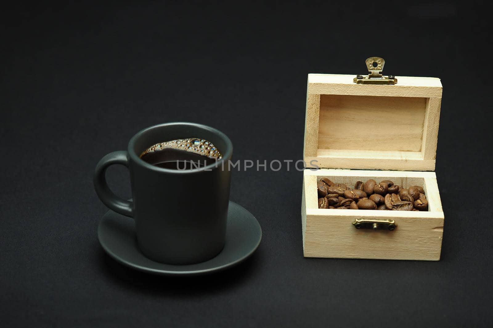 A cup of black coffee and coffee grain in a beautiful box. Black background. Close-up. High quality photo