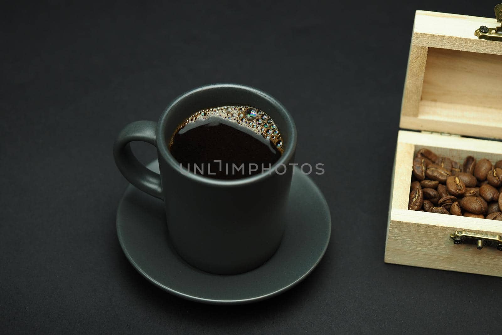 A cup of black coffee and coffee grain in a beautiful box. Black background. Close-up. High quality photo