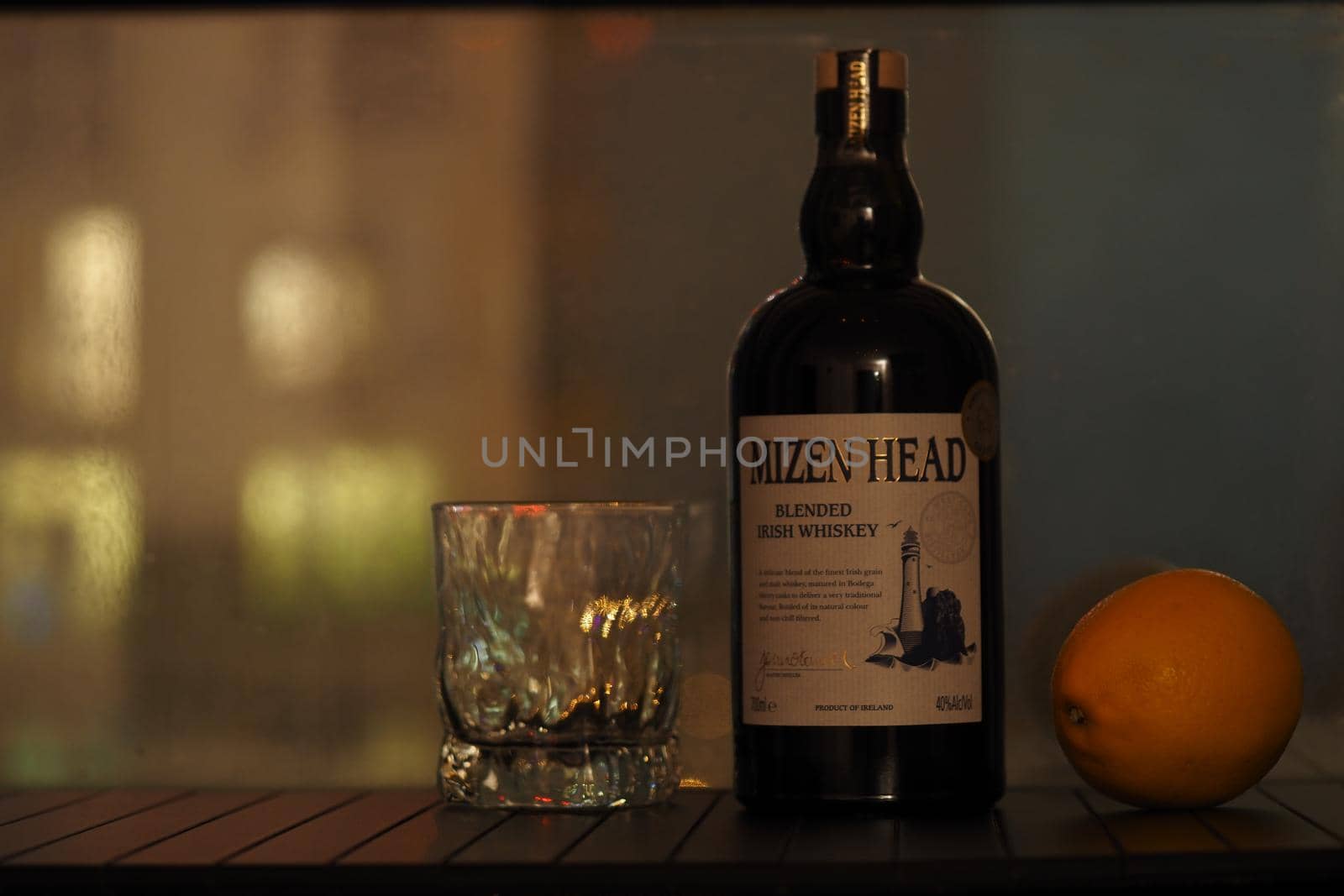 A bottle of Irish whiskey is a transparent glass and lemon on a black background. High quality photo