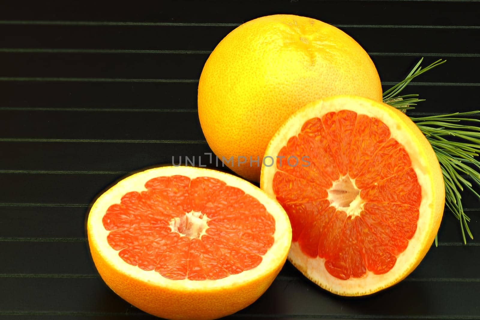 Citrus fruits. Cut grapefruit close-up on a black background. by Olga26